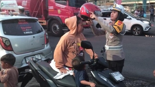 Kasat Lantas Polres Bitung, AKP Dwi Dea Angraini, S.I.K., M.H., saat memberikan Helm ke pengendara motor yang tidak memakai Helm. Selasa, 18/11/2025. (Foto.Humas Polres)