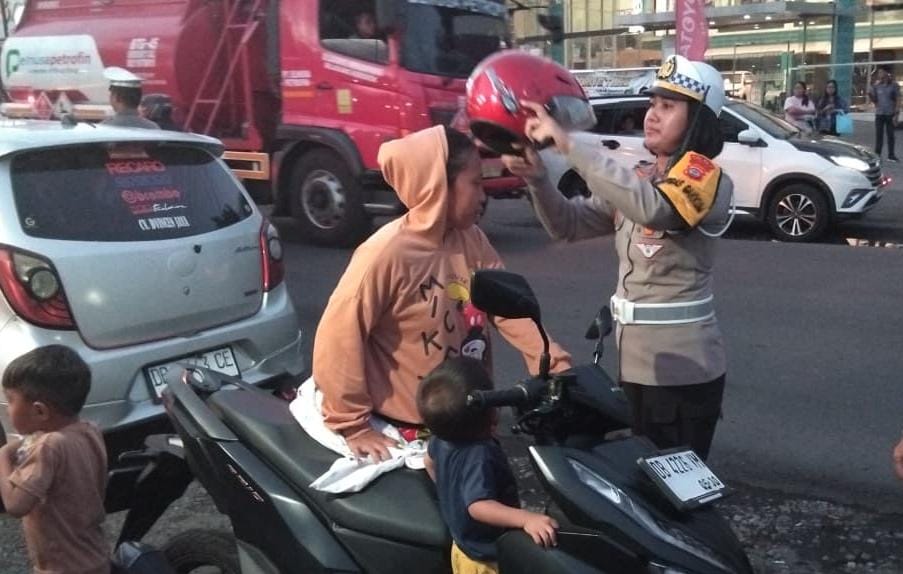 Kasat Lantas Polres Bitung, AKP Dwi Dea Angraini, S.I.K., M.H., saat memberikan Helm ke pengendara motor yang tidak memakai Helm. Selasa, 18/11/2025. (Foto.Humas Polres)